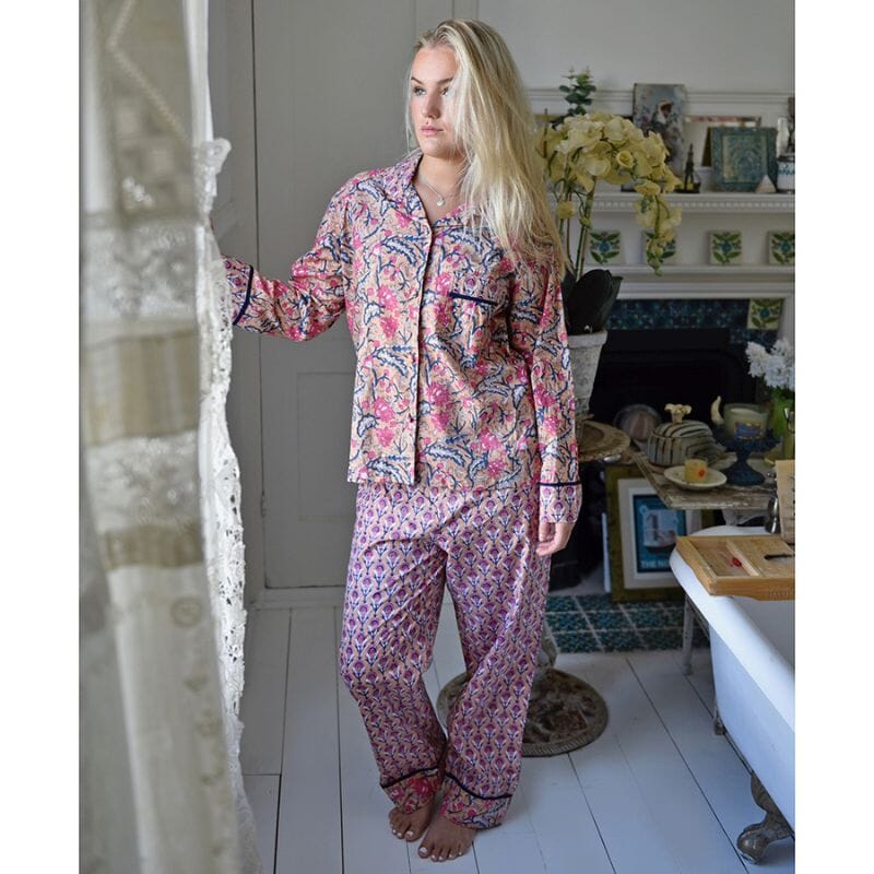 Powell Craftin pyjama vaaleahiuksisen naisen yllä. Kuosissa on aprikoosinsävyisellä pohjalla laivastonsinisiä ja persianpunaisia kuvioita, erilaisia ylä- ja alaosassa.