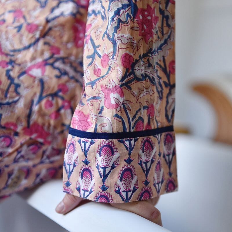 Yksityiskohta Powell Craftin pyjamamn hihasta. Kuosissa on aprikoosinsävyisellä pohjalla laivastonsinisiä ja persianpunaisia kuvioita.