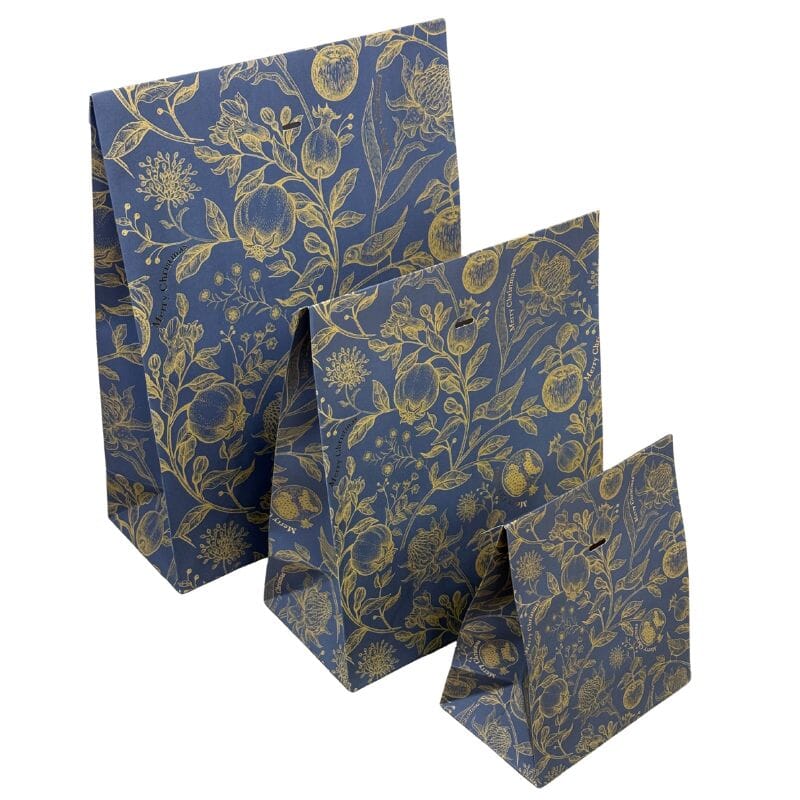 Kolme eri kokoista Kultalintu -lahjapussia sävyssä sininen, joissa tummansinisellä pohjalla kultaisia kukka- ja hedelmäköynnöksiä, joiden keskellä pieni kultainen lintu. 