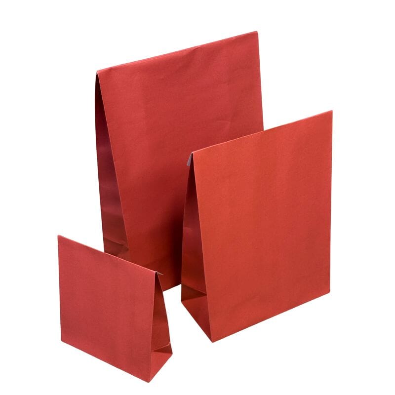 Punaisia yksisävyisiä lahjapusseja kolmessa eri koossa, valkoisella taustalla.