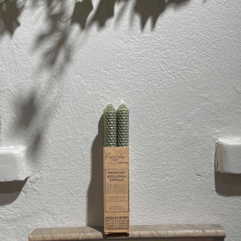 Salvian väriset mehiläisvahakynttilät 4 kpl paketissa valkoista seinää vasten.