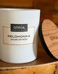 Osmia Kelohonka - tuoksukynttilän avoin kansi nojaa purkkiin, asetettuna rustiikkisen vanhan puulaatikon päälle. Kelopuun tuoksu sopii hyvin yhteen luonnonmateriaalien kanssa. 
