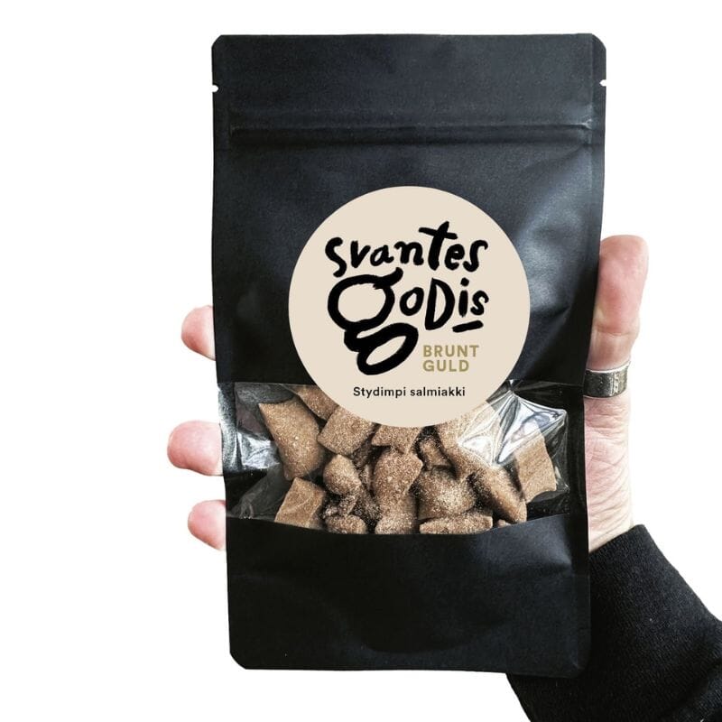 Svantes Godis Brunt Guld Stydimpi Salmiakki 100g mustassa pussissa, jonka pienestä ikkunasta näkyy herkulliset salmiakkikaramellit.