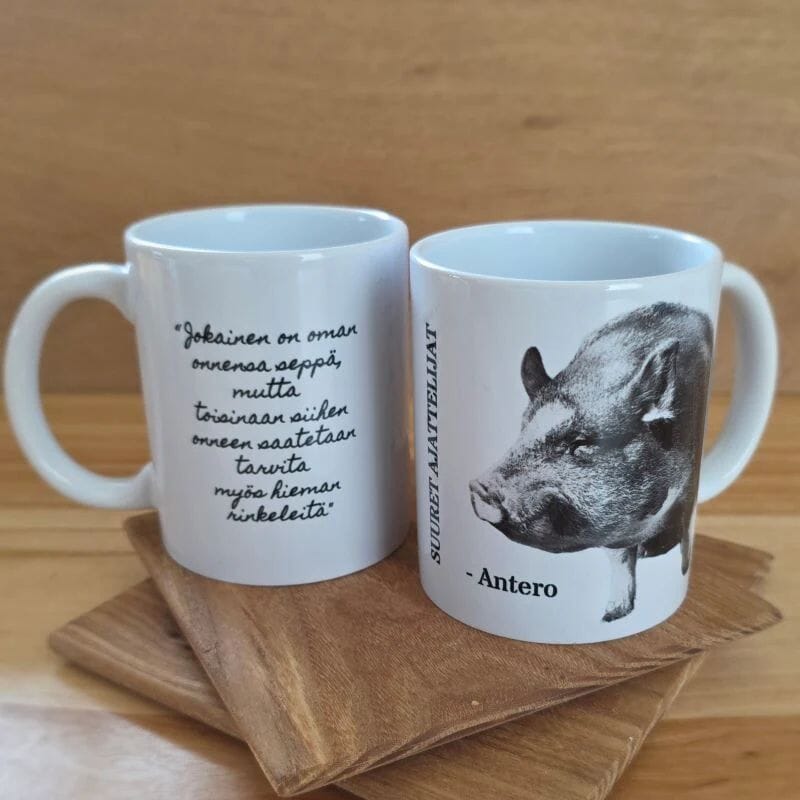 Tiluksilla Suuret ajatteiljat Antero-muki, jossa toisella puolella kuva Antero-possusta ja toisella teksti "Jokainen on oman onnensa seppä, mutta toisinaan siihen onneen saatetaan tarvita myös hieman rinkeleitä". 