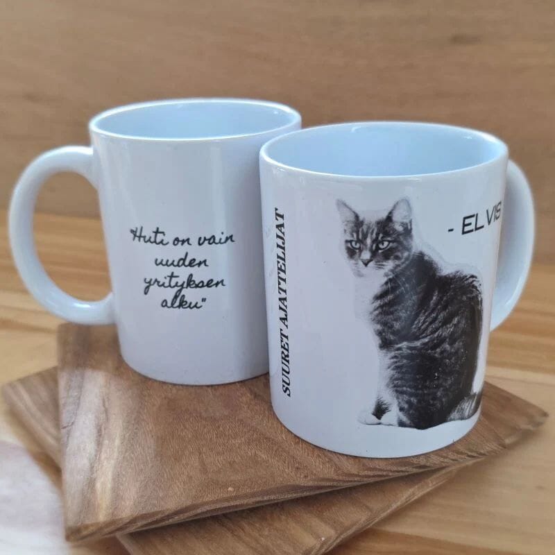 Tiluksilla Suuret ajattelijat Elvis-muki, jossa toisella puolella kuva Elvis-kissasta ja toisella teksti "Huti on vain uuden yrityksen alku".