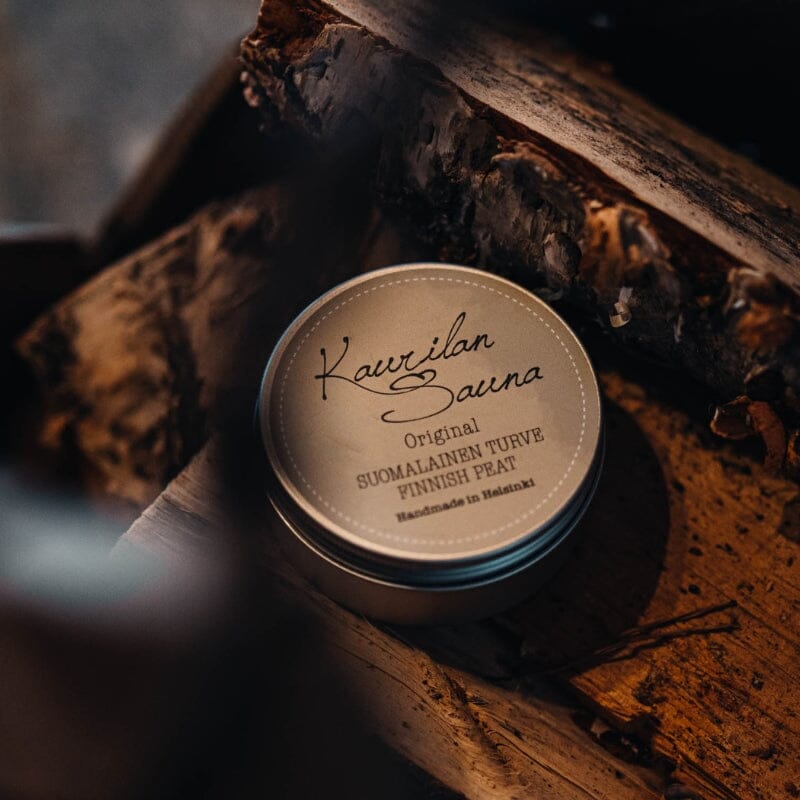 Kaurilan Saunan Tontun Saunasettiin kuuluva Suomalainen turvenaamio halkokorissa, tunnelmallisessa valossa.