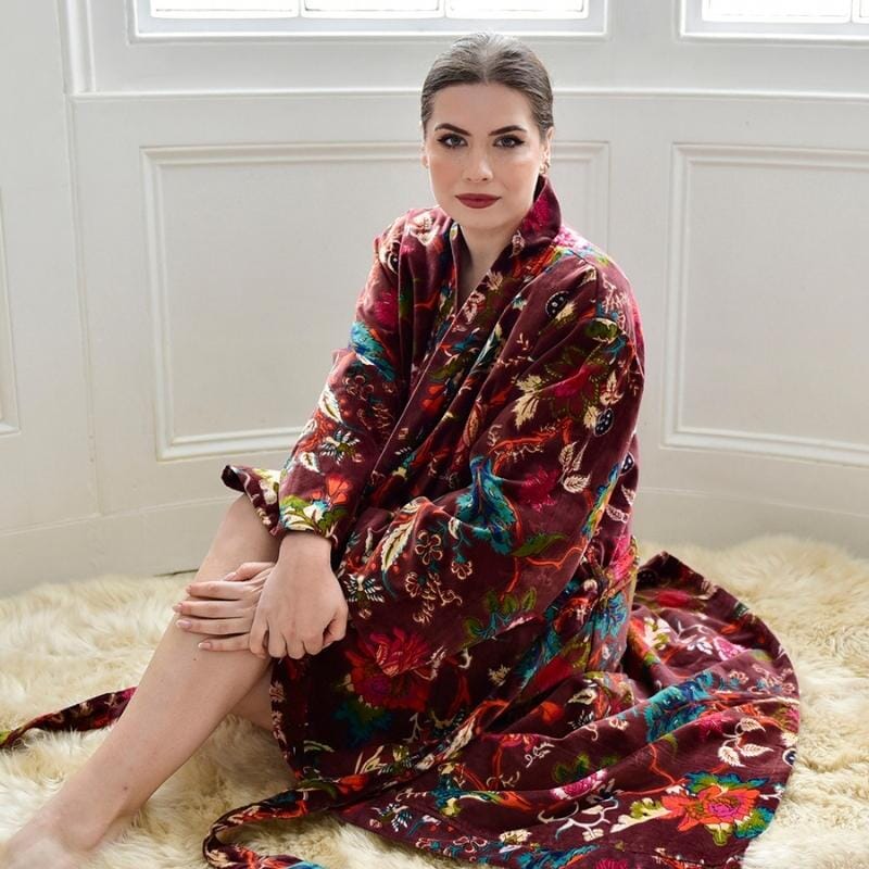 Powell Craft Velvet burgundy floral naisten puuvillainen kimono-aamutakki lampaantaljalla istuvan naisen yllä. 
