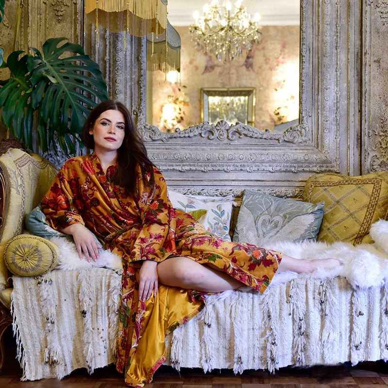 Powell Craft Velvet Mustard Floral naisten puuvillaveluurinen kimono-aamutakki antiikkisella sohvalla lepäävän naisen yllä.