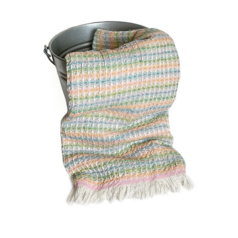 Saunatonttu by Kaurilan saunan Liisin Hamam-vohvelipyyhe sävyssä Kirjava pastelli, jossa vihreän, sinisen, oranssin ja vaaleanpunaisen sävyjä, sekä päissä vaaleat kevyet hapsut.