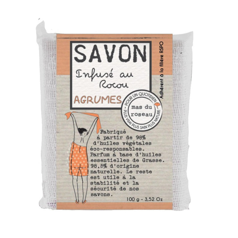 Mas du Roseaun sitruksentuoksuinen 100 gramman palasaippua kangas- ja paperikääreessä, jossa piirretty kuva naisesta pyyhe päällä ja ranskankielistä tekstiä.